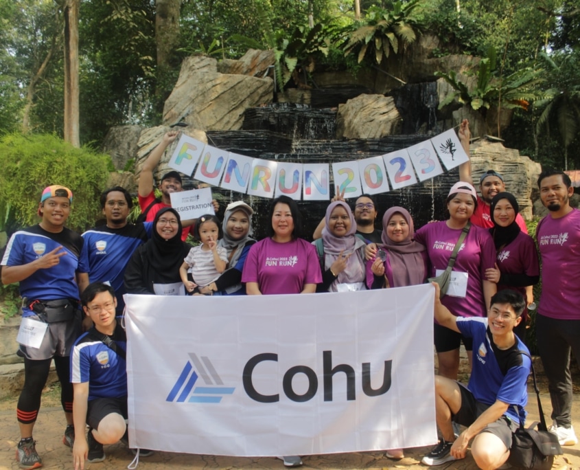 A group of 16 people smiling in a group outside holding a banner that reads Cohu and individual letters that spell out Fun Run 2023.